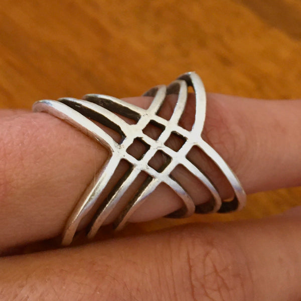 Model wearing our featured ring on her finger. Ring is:  Multi-cross mixed metal silver colored Turkish made ring with an adjustable band. Lightweight statement ring  with 1 inch height on the top wave, with a center half inch. A wave of bands with a woven 4 diamond shaped stamp in the middle.  Usual and Unique styled rings made just for you.