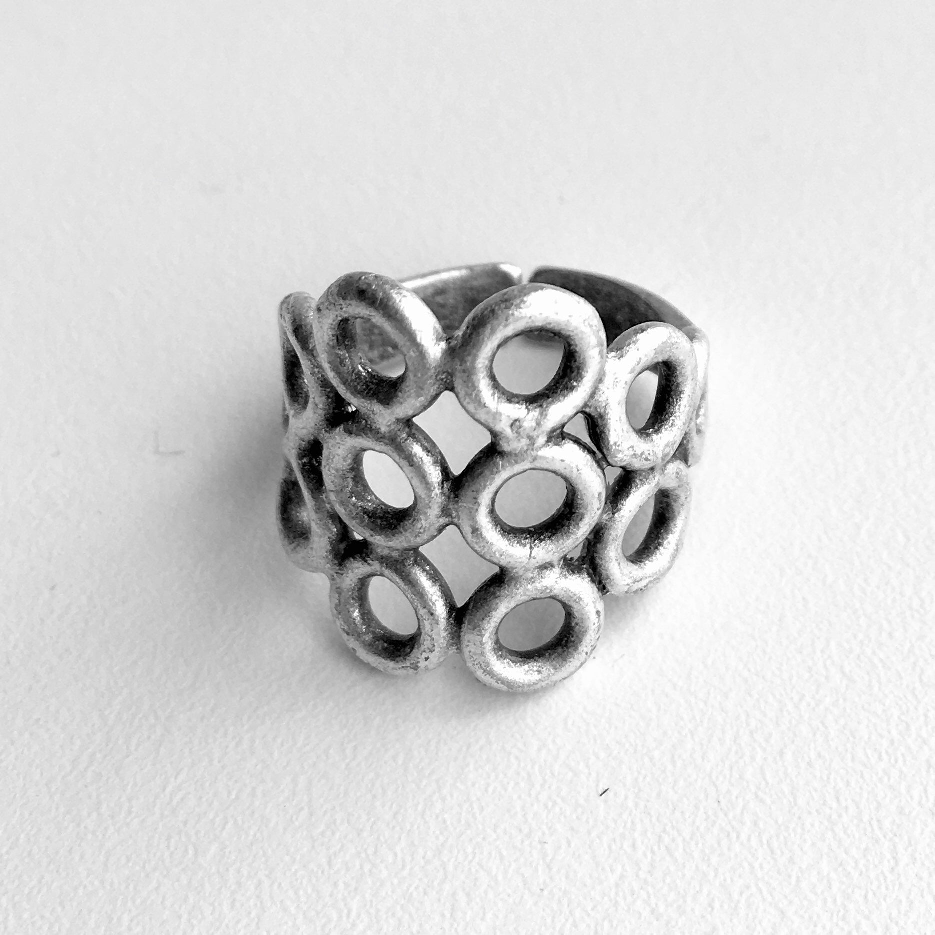 Turkish made silver colored mixed metal ring with 6 center cut out circles in rows of 3 with a row of 2 circles on either side, finishing with one circle next to the row of 2.  3/4 inch from top to bottom from the largest part of the ring, front. 