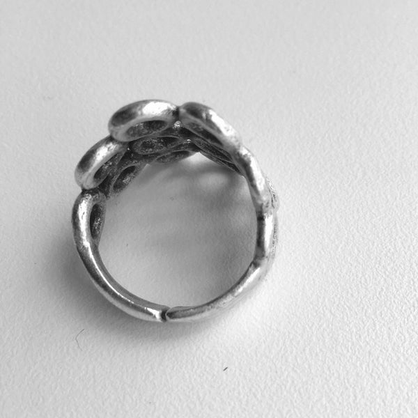 Closer top view of Ring. Turkish made silver colored mixed metal ring with 6 center cut out circles in rows of 3 with a row of 2 circles on either side, finishing with one circle next to the row of 2.  3/4 inch from top to bottom from the largest part of the ring, front. 