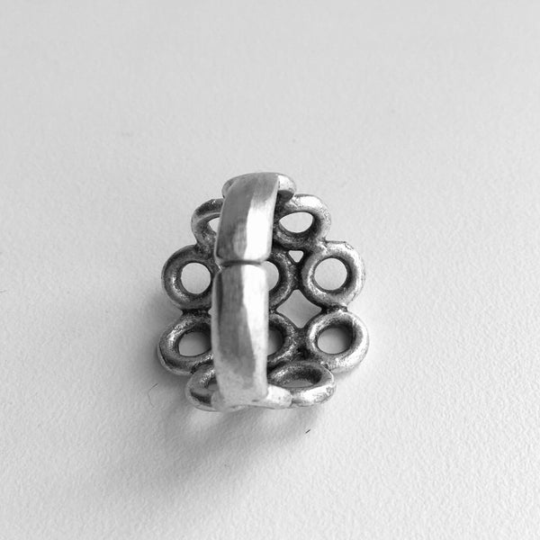 Back side showing the adjustable band from its base size 7.5 -8 of Turkish made silver colored mixed metal ring with 6 center cut out circles in rows of 3 with a row of 2 circles on either side, finishing with one circle next to the row of 2.  3/4 inch from top to bottom from the largest part of the ring, front. 