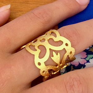 Model wearing our featured ring on her center finger Lacy cut out ring with a hint of Regal days long gone by way of this Renaissance styled gold colored brass lightweight ring made in Turkey. Adjustable Band lets you start on your size 7 finger, and move up in size. 