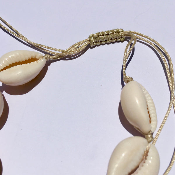 WHITE COWRIE SHELL CORD NECKLACE STRUNG ON A NATURAL COLORED CORD AND EASY KNOT CLOSURE FOR ADJUSTING THE LENGTH. GREAT NECKLACE FOR SUMMER AND ISLAND LIFE. VERY LIGHT AND EASY TO WEAR. MADE IN TURKEY FOR US. perfect braided knot closure is shown