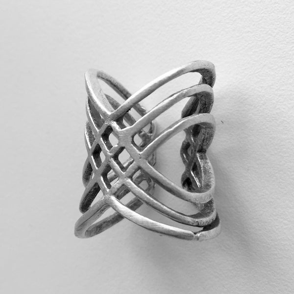Side view of  Multi-cross mixed metal silver colored Turkish made ring with an adjustable band. Lightweight statement ring  with 1 inch height on the top wave, with a center half inch. A wave of bands with a woven 4 diamond shaped stamp in the middle.  Usual and Unique styled rings made just for you.